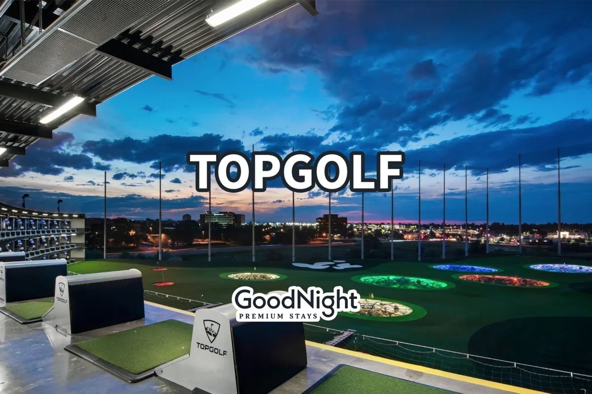 A lively night scene at Topgolf, with golf bays overlooking a brilliantly lit range and the city skyline in the background. The energetic setting suggests friendly competition, group fun, and unique recreational opportunities.