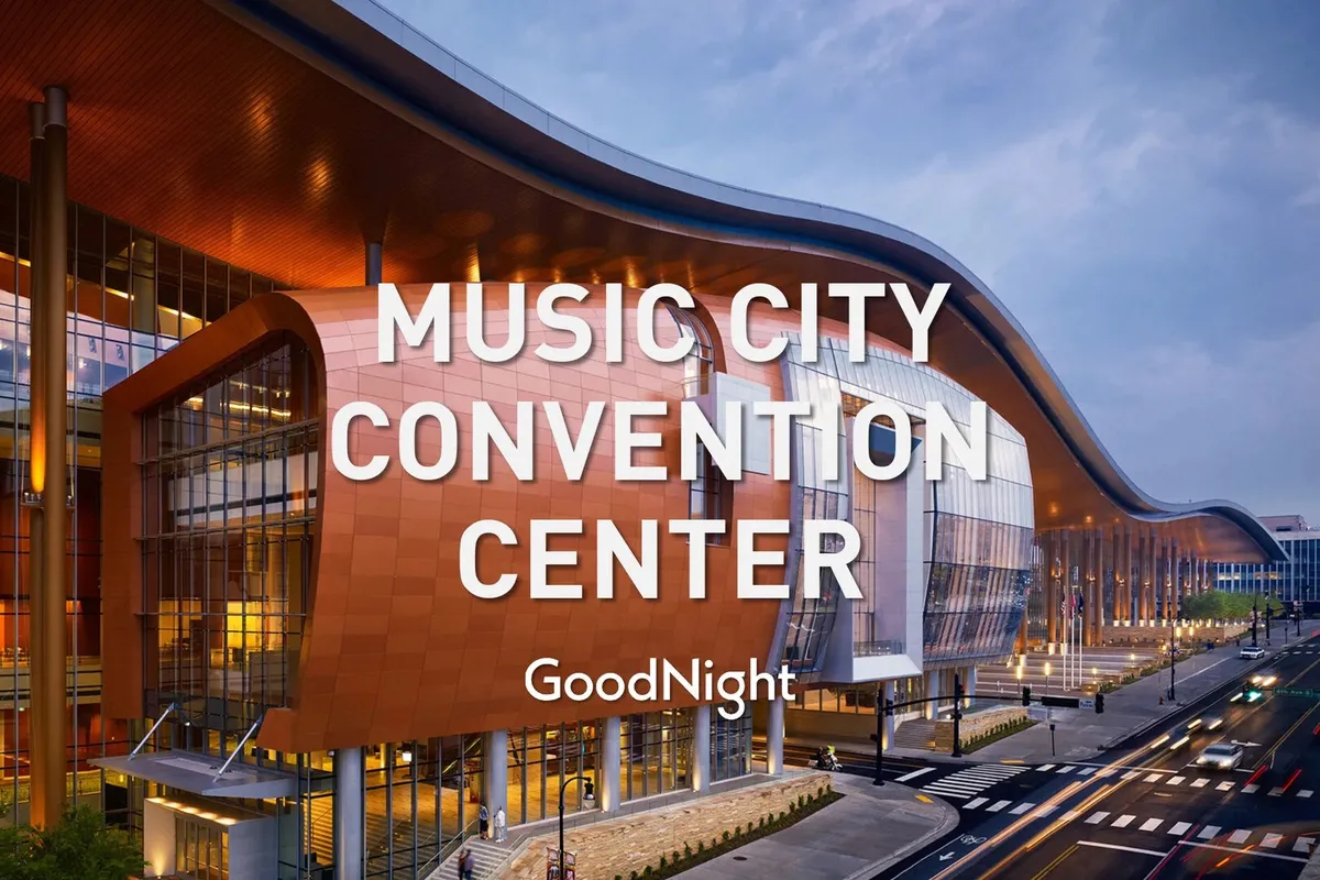 An exterior shot showcasing the unique architectural design of the Music City Convention Center, complete with illuminated signage and a lively urban backdrop. The scene captures the energy of Nashville's business and event district.