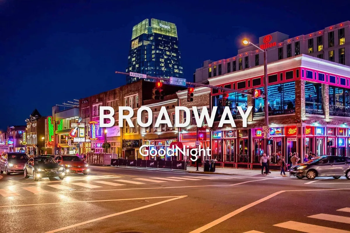 A lively nighttime view of a bustling street in Nashville, illuminated by colorful neon signs, streams of cars, a lively crowd, and vibrant city lights. The energy of the music scene and nightlife is palpable, capturing the excitement right outside the Opulent Pearl.